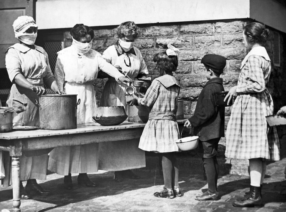 #4 Volunteers wearing masks feed children of stricken families.