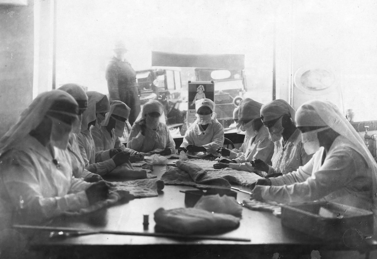 #13 Combatting influenza in Seattle in 1918. At work in the Red Cross rooms in Seattle, Washington, with influenza masks on faces.