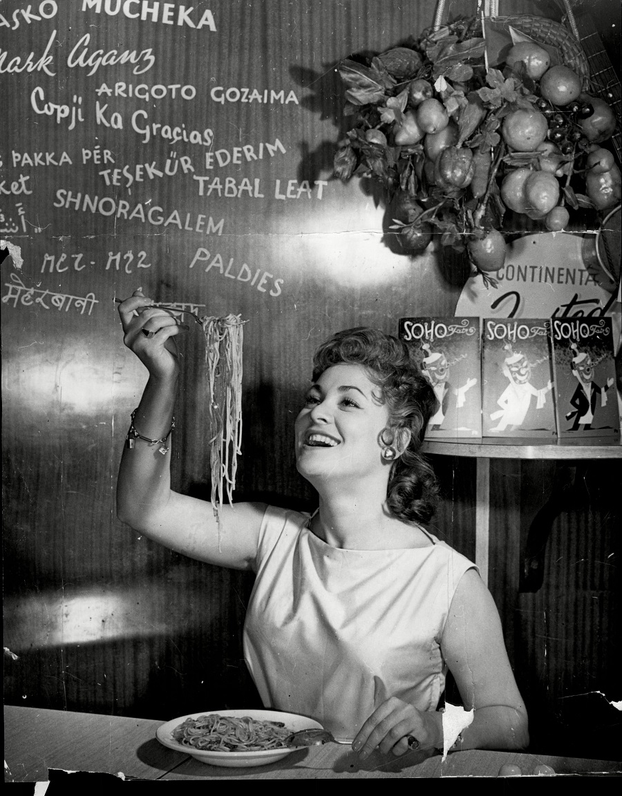 #38 Soho’s Fair Queen Andria Loran (real Name Maureen Smith) tries her skill at Spaghetti Eating, July 1956.