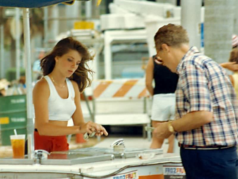 #4 An attractive young lady makes change for a customer at a frozen snack cart, SunFest, 1988