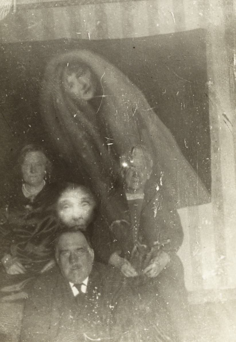 #17 The spirits of an elderly woman and a younger woman appear over a group photo.