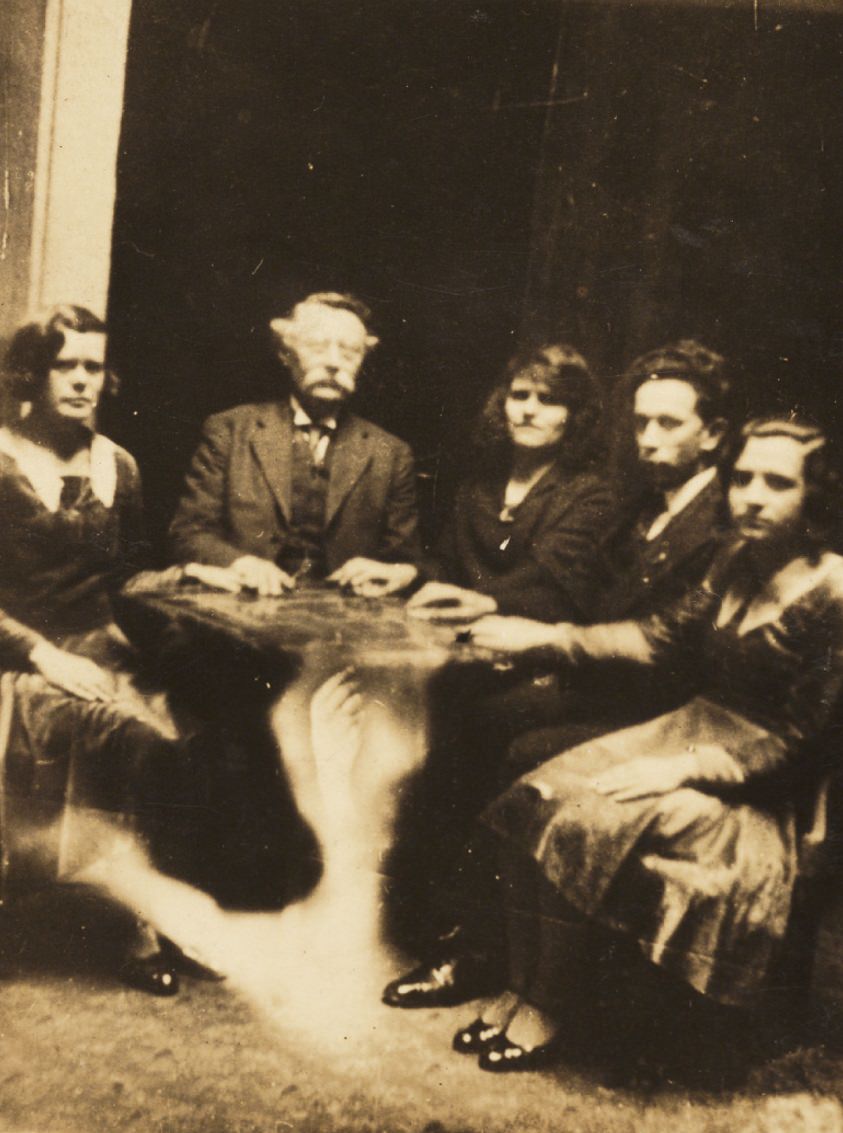 #3 A seance with a ghostly arm superimposed under the table.