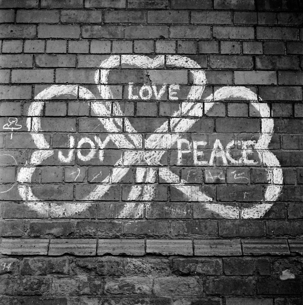#35 A painted sign on a wall in Belfast reading ‘Joy, Love, Peace’ in the shape of a shamrock, 1954.