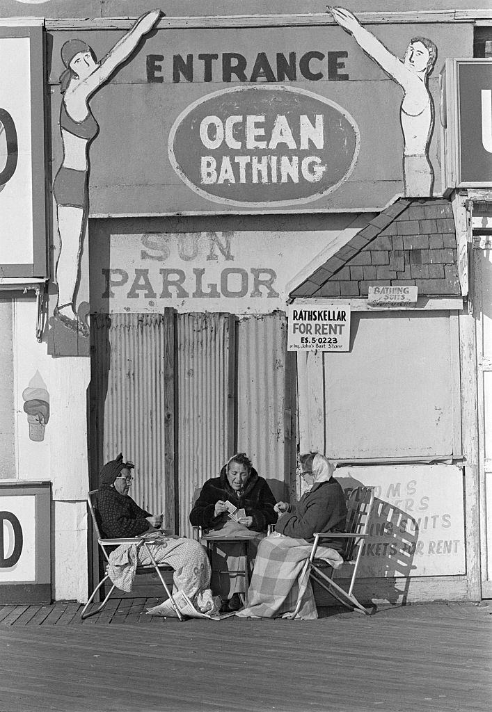 #6 Bundled up against the cold, three elderly women play a game of cards in front of a bathhouse on the Coney Island boardwalk. December 11, 1959.
