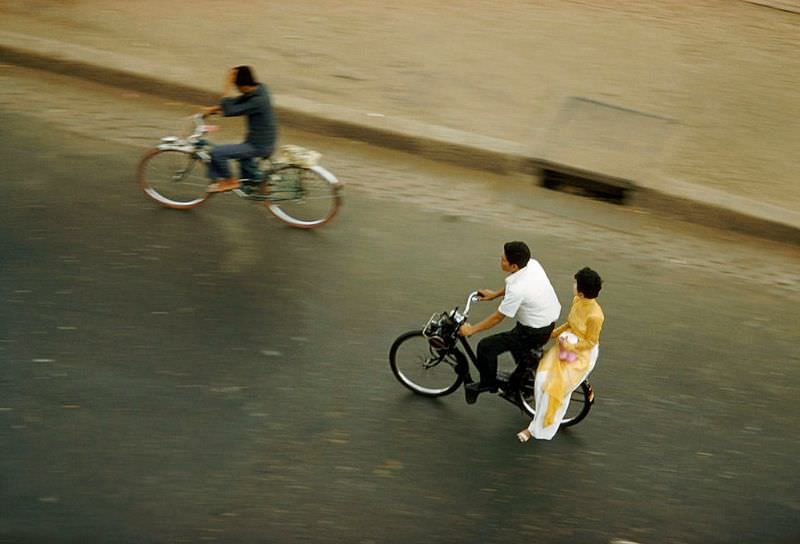 #8 A man and a traditionally dressed woman speed by on a motorbike in Saigon, 1961