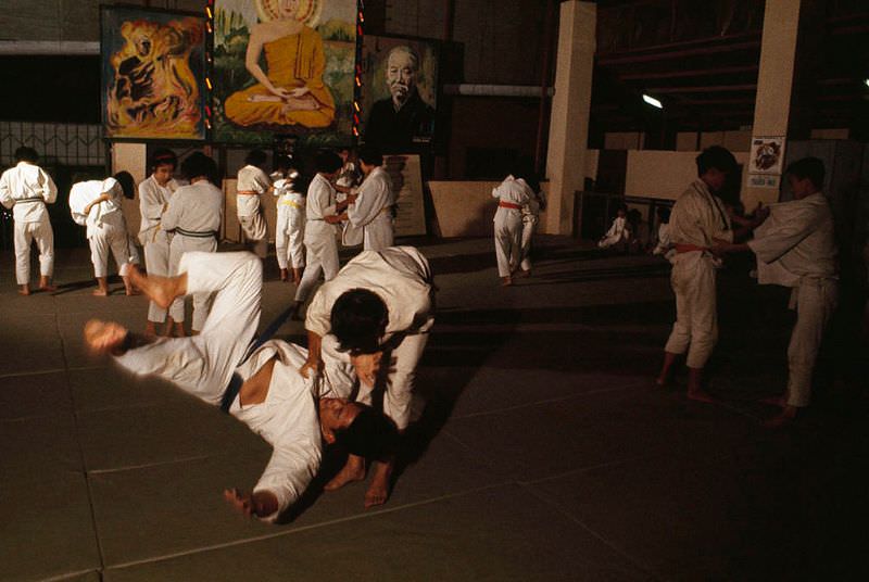 Judo students practice below images of revered figures of Buddhism in Saigon, 1965