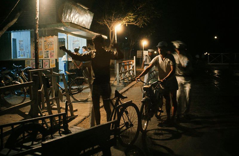 #31 Policemen examine people lined up at a security gate to enter a city, 1965