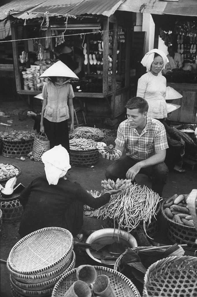 #20 Volunteer Verle Lanier (center R) buying bananas at market, 1961.