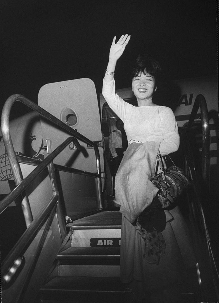 #46 Madame Ngo Dinh Nhu waving from the stairs of an airplane, 1963.