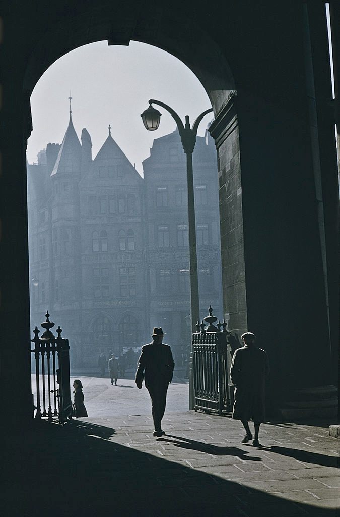 #18 Pedestrians walking through an arched gateway in Belfast, 1955.