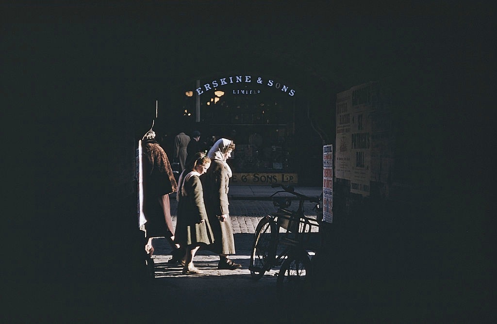 #20 Pedestrians on a shopping street, seen through an archway, Belfast, 1955.