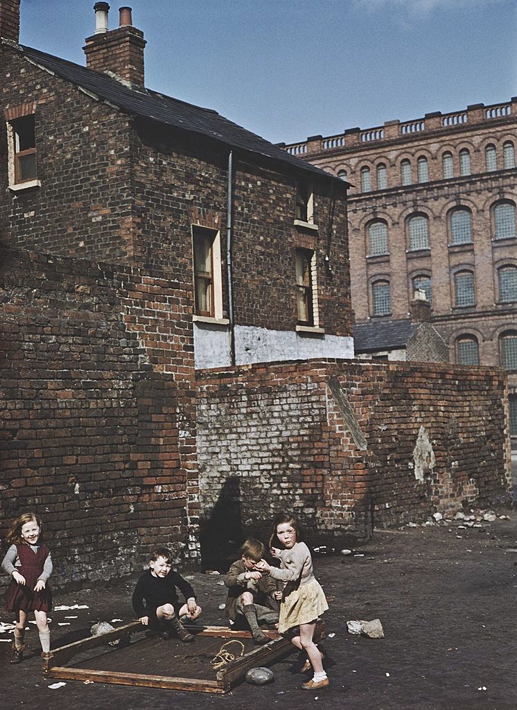 #8 A group of children playing with an old bed frame on waste ground in Belfast, 1955.