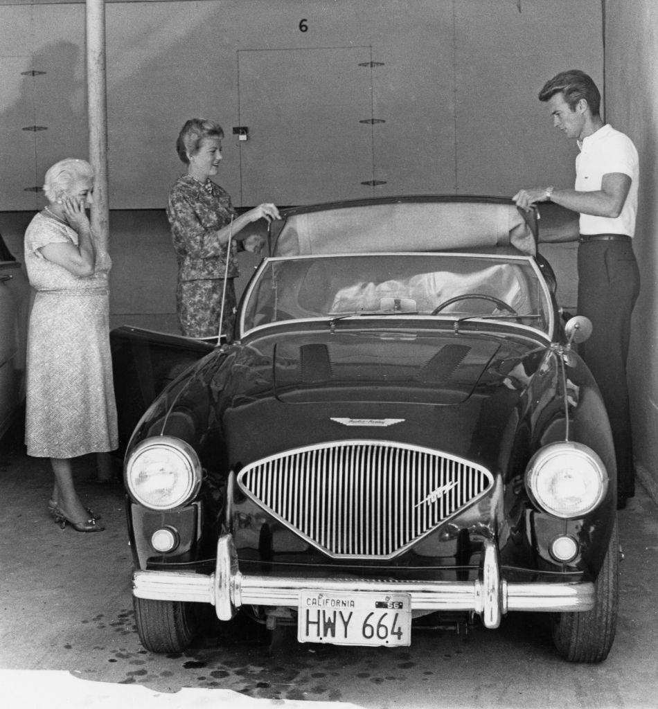 #22 Clint Eastwood and with his wife Maggie Johnson adjusting the roof of an Austin Healey sports car, 1960.