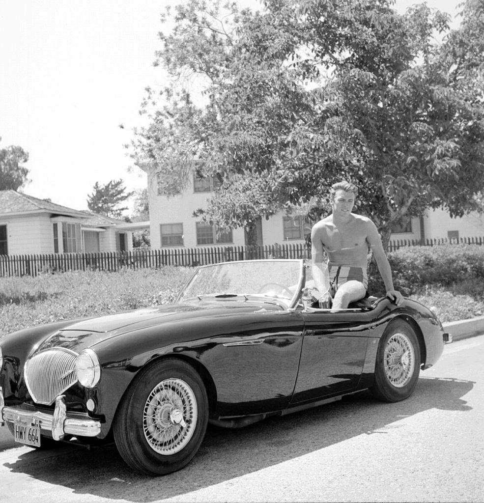 #7 Clint Eastwood sits the back of a convertible Austin Healey sportscar, 1956.