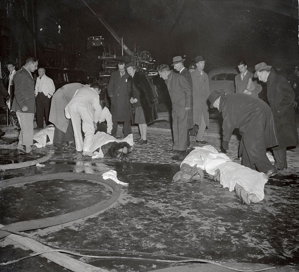 Bodies of four victims of the fire that destroyed Boston’s popular Cocoanut Grove Night Club last night (November. 28) lie in the street, waiting removal to the city’s overcrowded morgues.