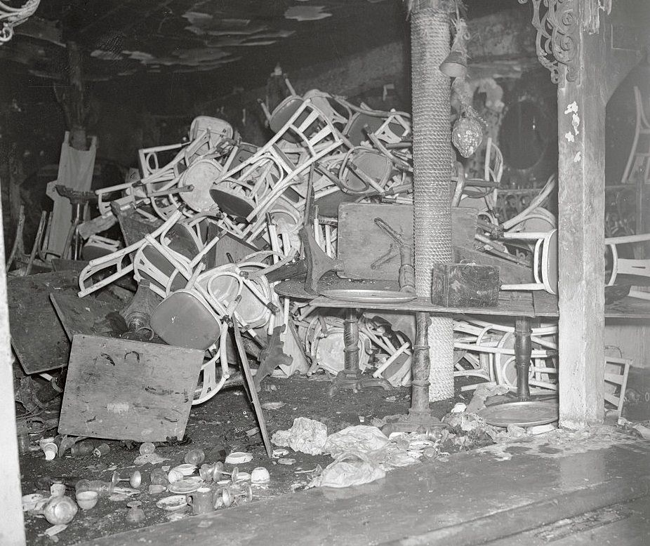 Charred tables and chairs, broken wine glasses and other debris clutter a section of Boston’s destroyed Cocoanut Grove Night Club.