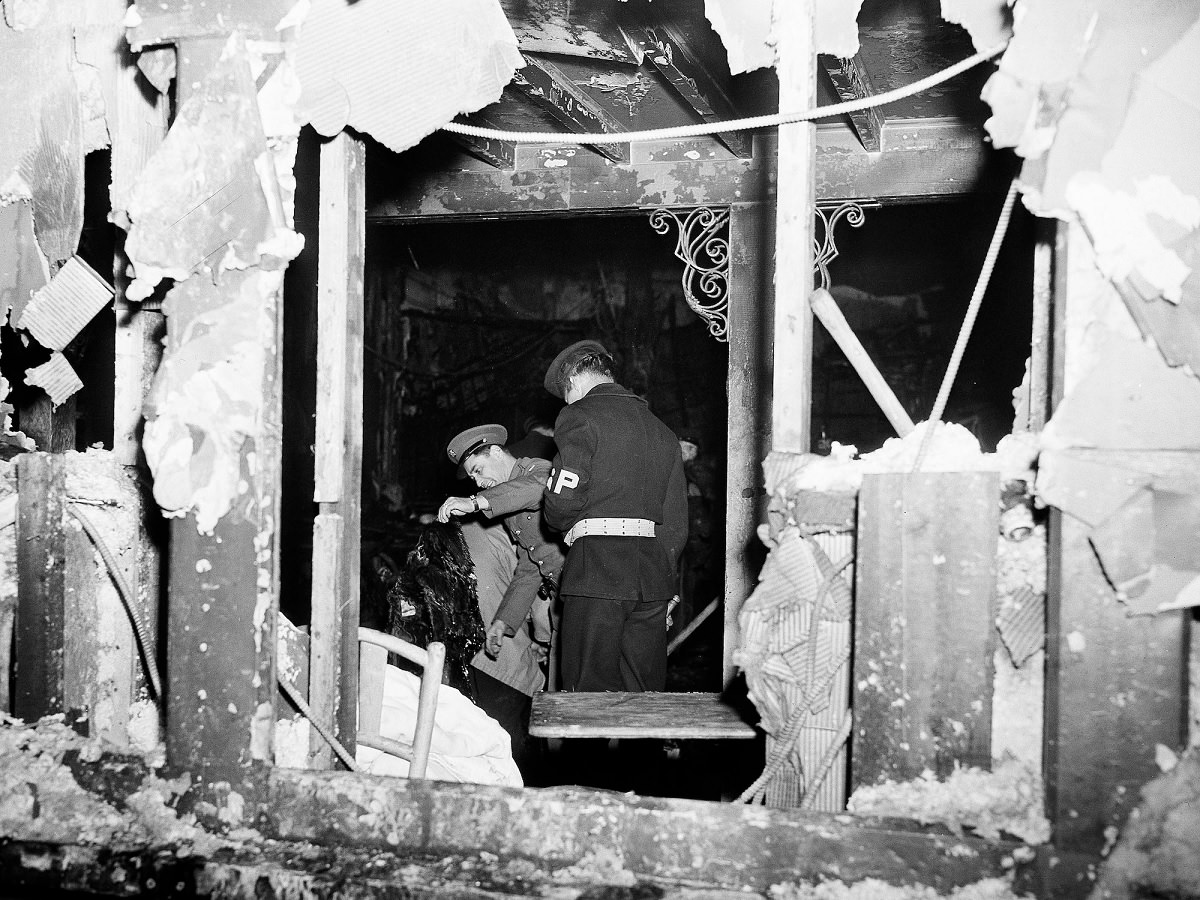 #51 A soldier and a member of the Navy’s shore patrol search through charred wreckage at the Cocoanut Grove night club.