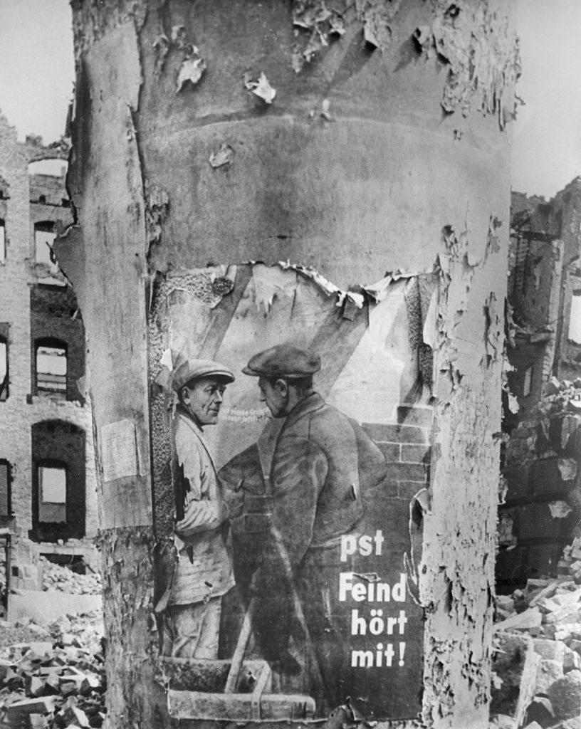 An advertising column with the remains of a Nazi poster which says “pst – Feind hört mit!”, 1945.