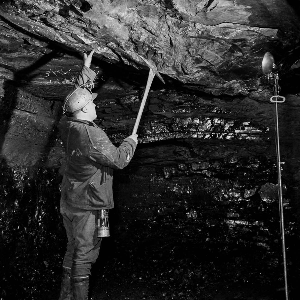 #9 A miner tests the stability of the tunnel roof.