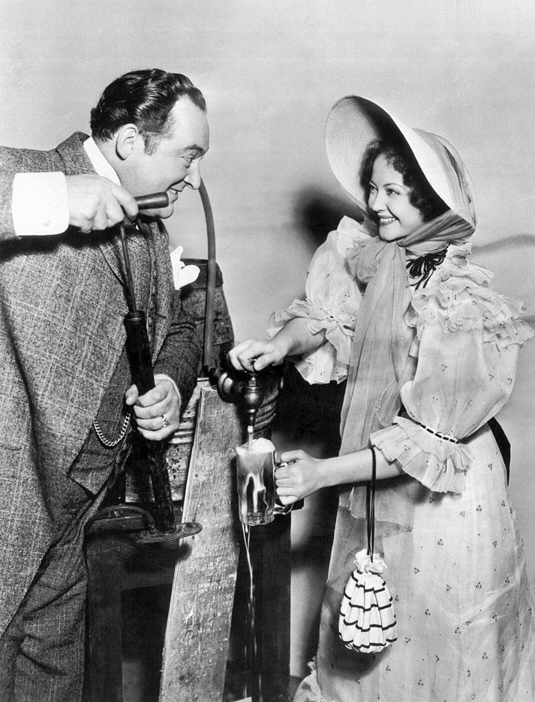 #20 Sylvia Sidney tapping a stein of beer for Edward Arnold as he pumps, 1933.