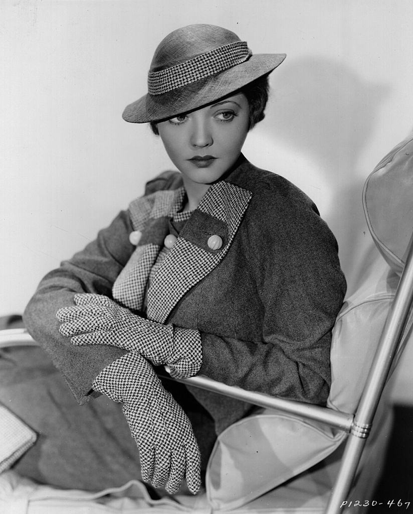 #36 Sylvia Sidney wearing a street suit in brown worsted with vest, lapels, gloves, handbag and hat band in brown and white check, 1934.