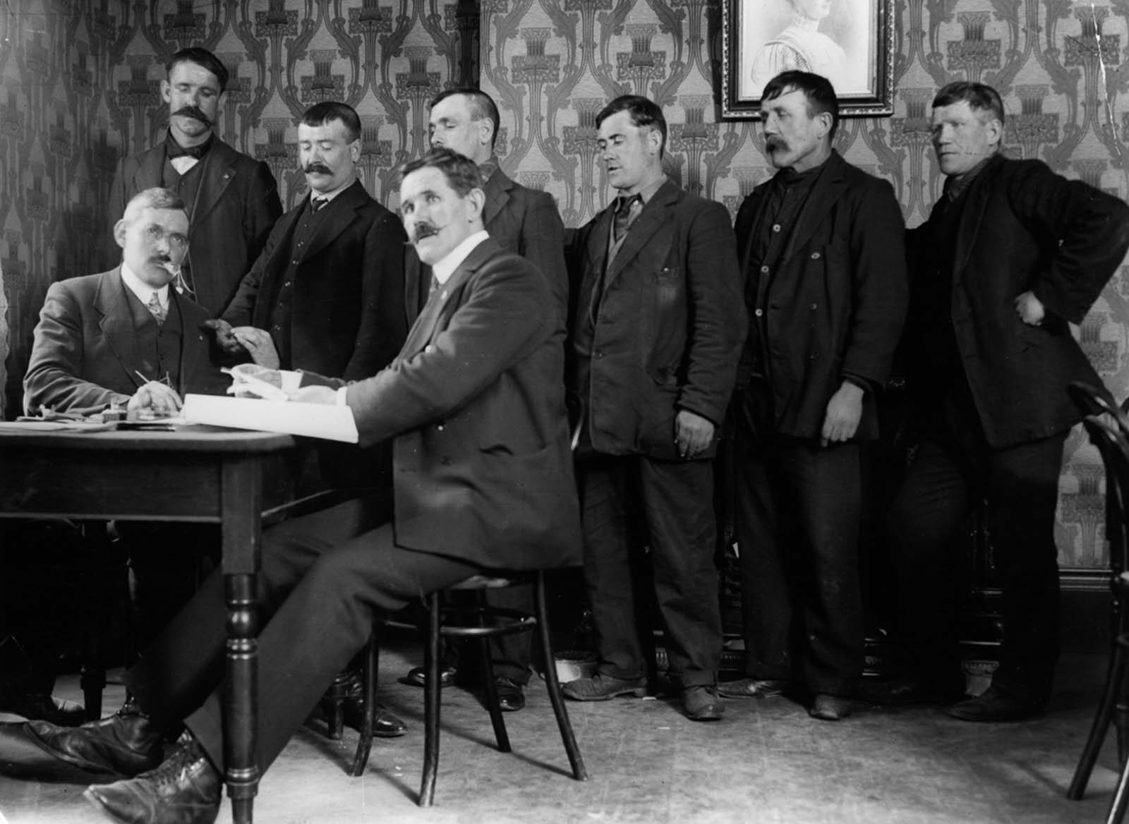 #15 J. Hanson, seated right, district secretary of the National Sailors and Firemen’s Union, awards shipwreck pay to survivors.