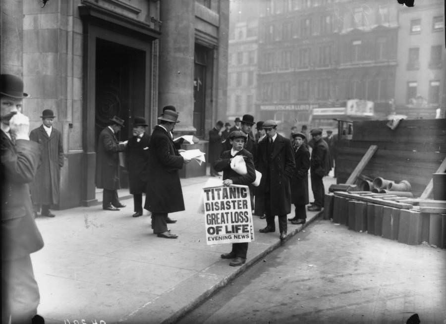 #29 A newspaper boy sells copies of the Evening News telling of the Titanic sinking outside the off ice of the White Star Line