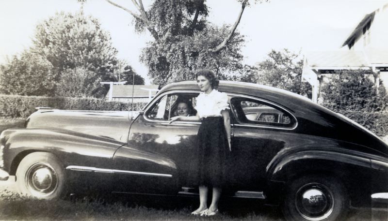 #14 A fashionable brunette lady posing with a 1947 Oldsmobile Dynamic Cruiser in summertime, 1948