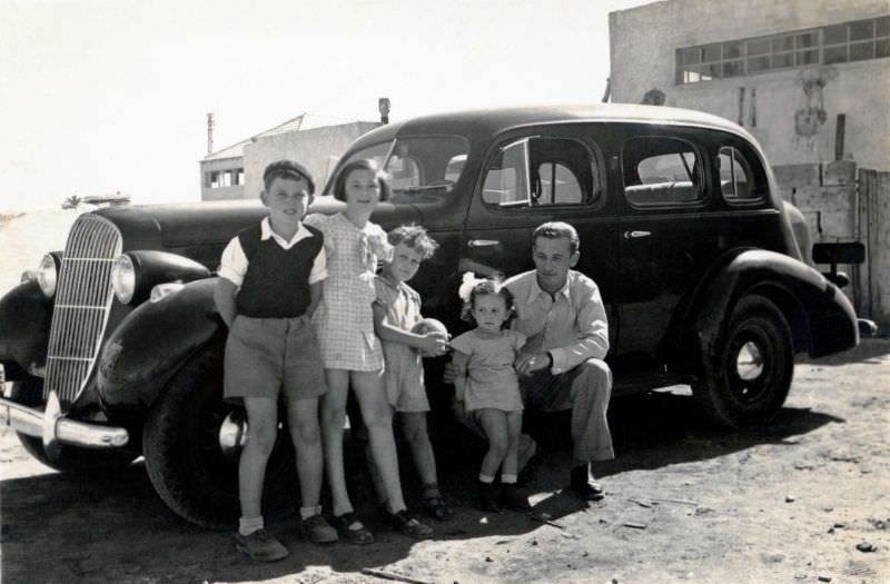 #21 A father and four of his children posing with a 1935 Oldsmobile 4-Door Touring Sedan in bright mid-day sunshine, Israel, 1950