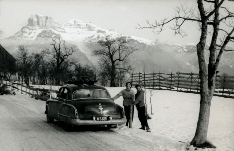 #30 Two cheerful ladies posing with a 1949 Oldsmobile 4-Door Sedan on a snow-covered road in the countryside.