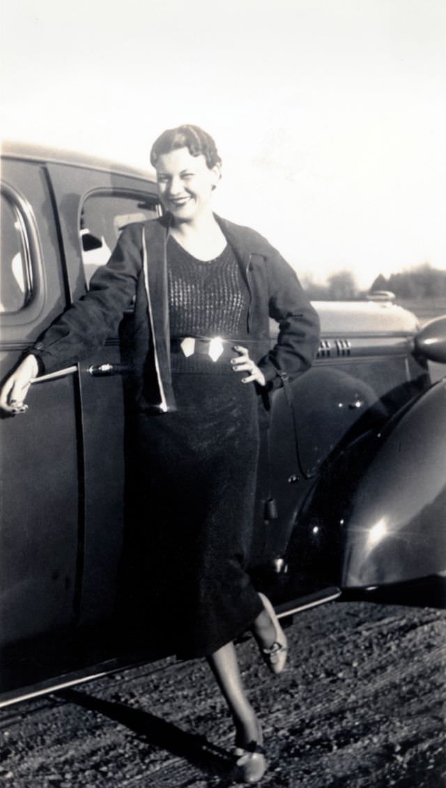 #4 A stylish lady dressed posing with a 1936 Oldsmobile Eight on a gravel road in late afternoon sunshine, 1938