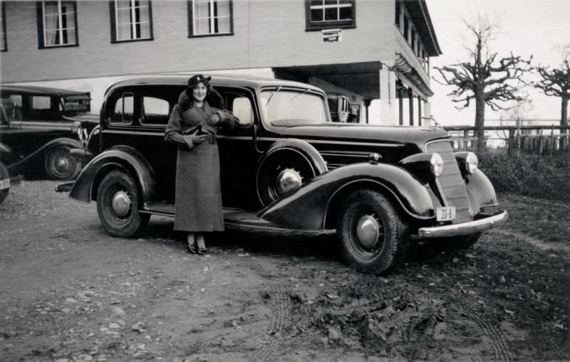 #5 An elegant young lady in a fur-collared coat posing with a 1934 Oldsmobile Eight on a bleak winter’s day, 1938