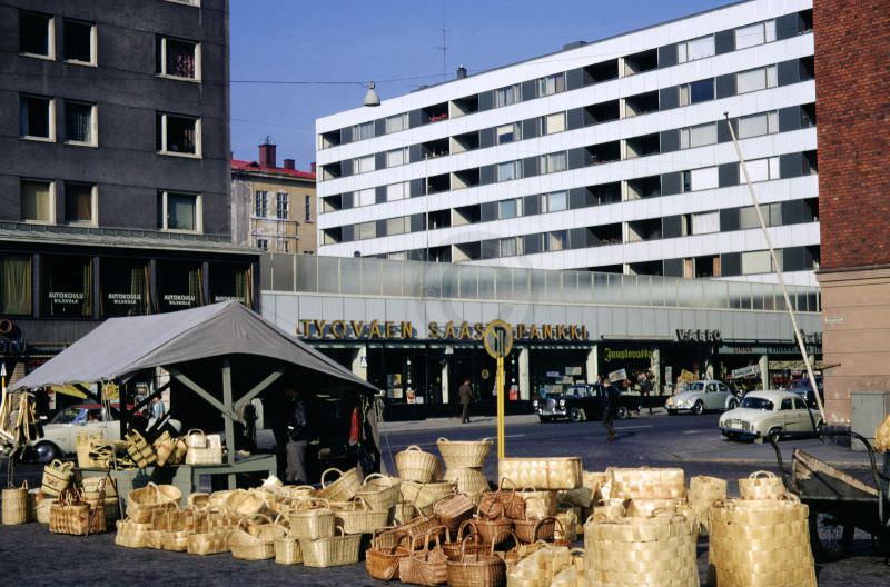 #18 Bags and baskets stand outside of a market stall in a neighbourhood market in Helsinki, 1968