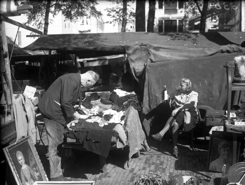 #14 Market on the Waterlooplein, woman reads newspaper behind her stall. Amsterdam, September 1946