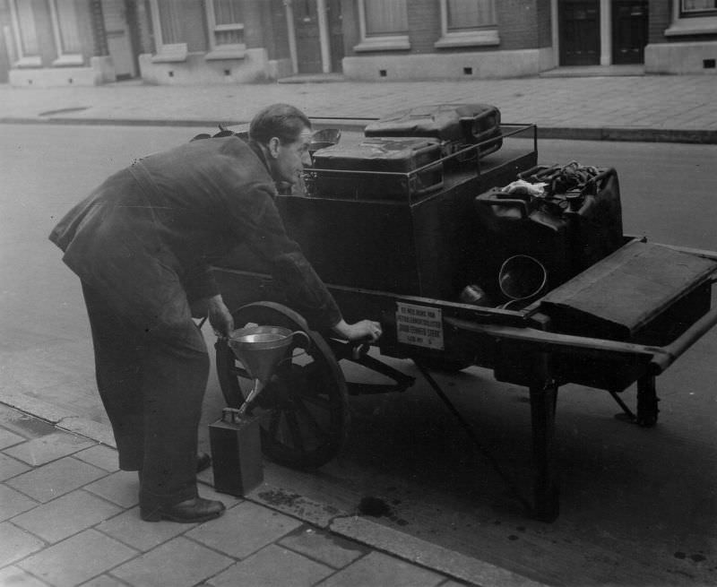 #38 Member no. 5 of the Dutch Association of Petroleum Dieticians ‘By Unity Strong’ fills an oil can on the street. Amsterdam, January 14, 1948