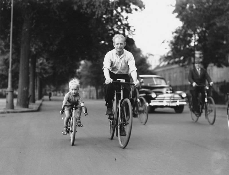 #49 Little boy riding a mini-road bike under the guidance of his father, Sarphatistraat. Amsterdam, July 13, 1949
