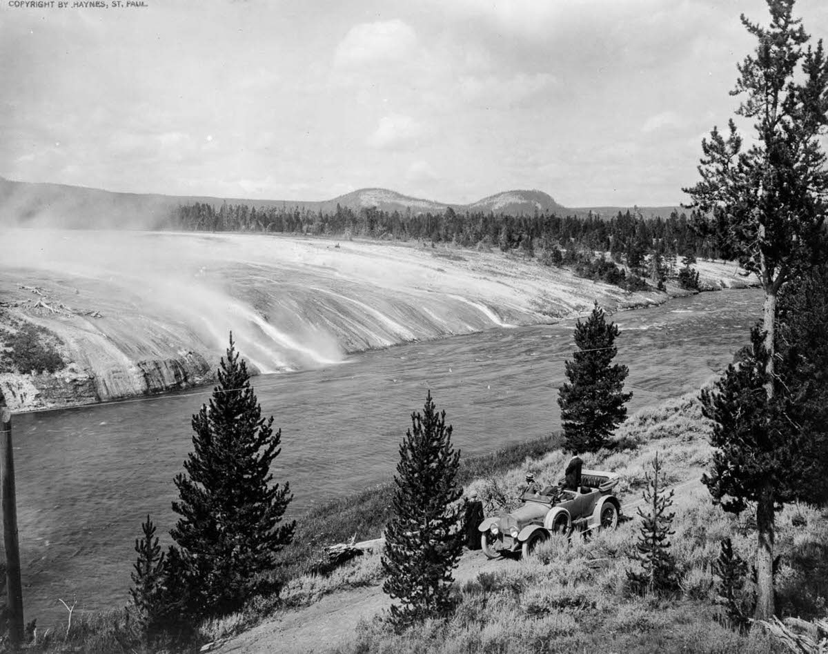 #21 Tourists watch the scalding water from the Excelsior Geyser flow into the Firehole River in Yellowstone, 1917.