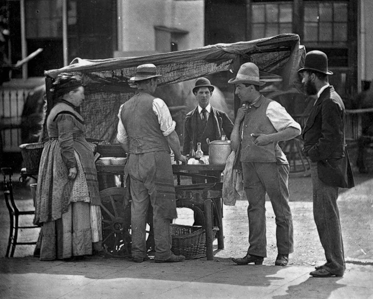 #1 A shellfish stall owner sells oysters and whelks, 1877.