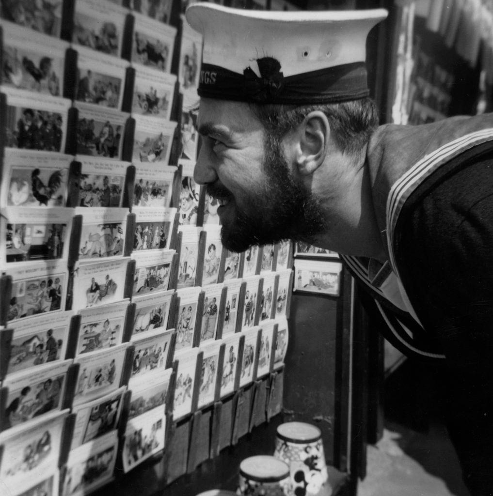#36 A sailor looking at a selection of postcards at the seaside in Blackpool, 1951.