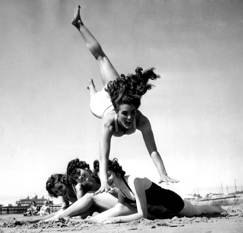 #50 Dancing teacher, Hazel Cleaver, leaps over her friends as they enjoy the summer sunshine on the beach, 1955.