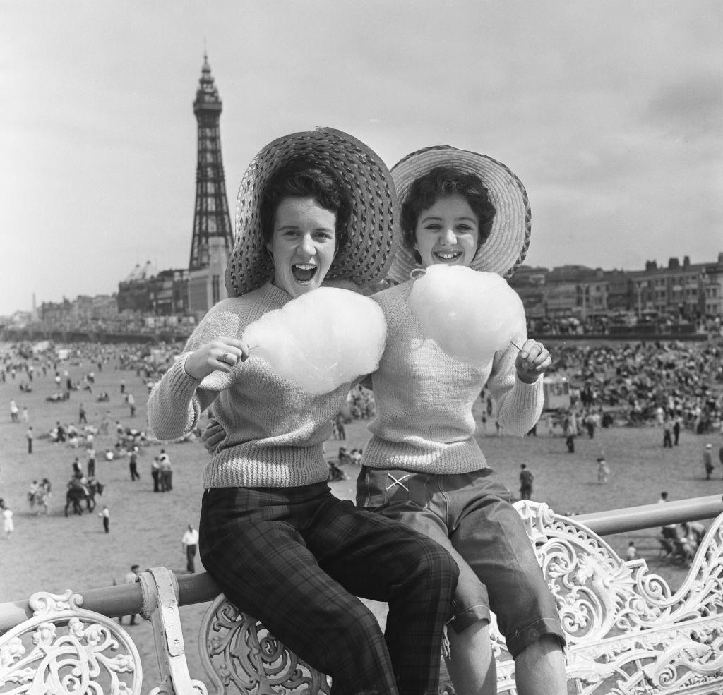 #62 Jean Clark and Mary Cuppler enjoy eating candy floss on the pier at Blackpool, 1957.