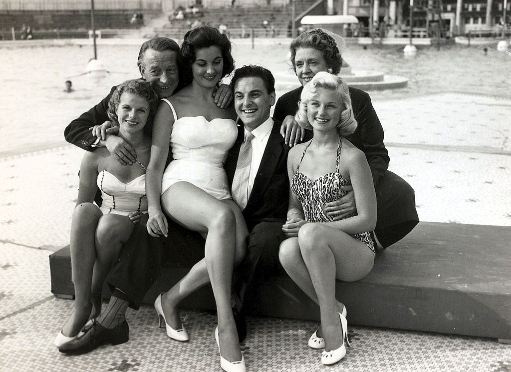 #65 British comedian Bob Monkhouse, centre with Wilfred and Mabel Pickles and beauty contestants at a beauty show at Blackpool, 1957.