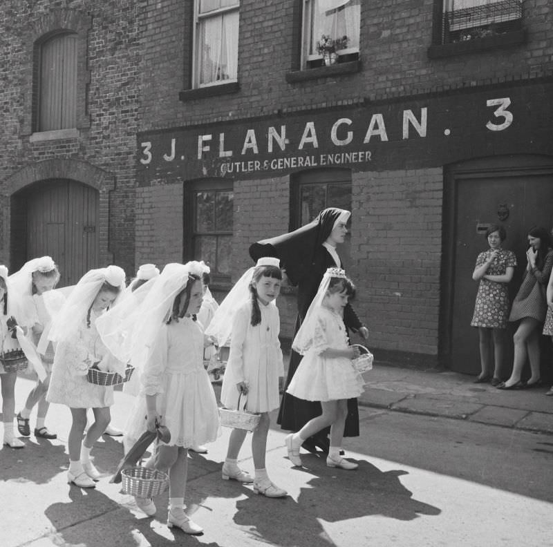 #21 A young nun walking Holy Communion girls past no. 3, Halston Street, Dublin on the feast of Corpus Christi, June 5, 1969