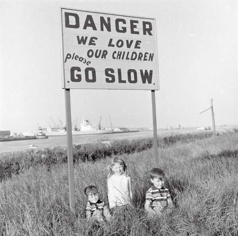 #23 Children under a sign designed to protect them on the Pigeon House Road, Ringsend, Dublin, 1969