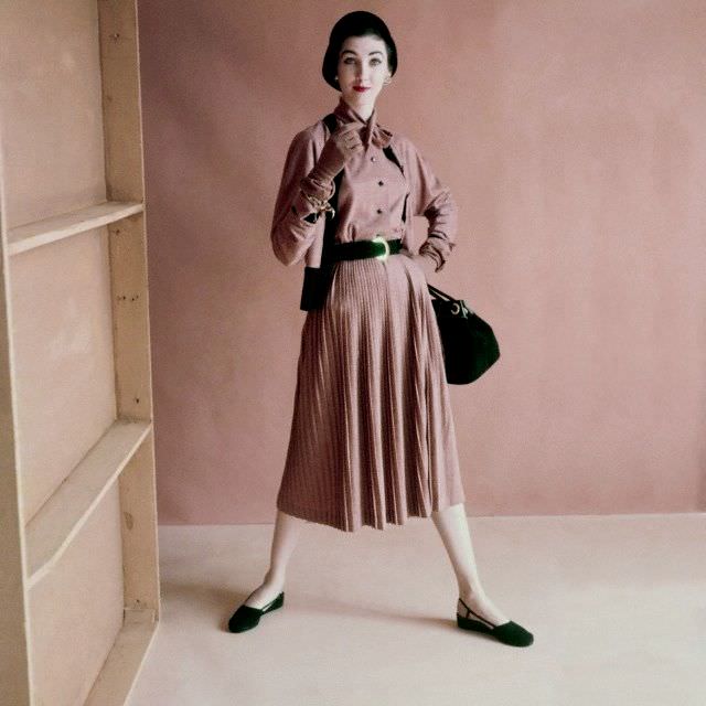 #4 Model is wearing a wool jersey blouse that ties at the neck, a wool jersey cardigan with black knit ribbing, and a slim pleated skirt in matching wool jersey, 1952