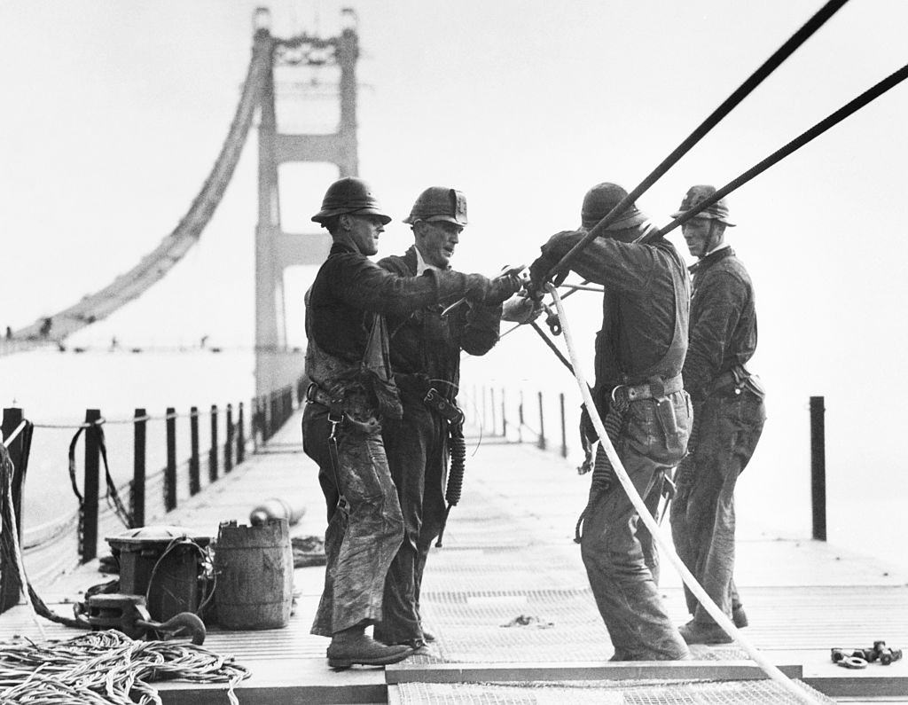 #25 Workers are shown standing on a catwalk working on the cables of the Golden Gate Bridge spanning San Francisco Bay.