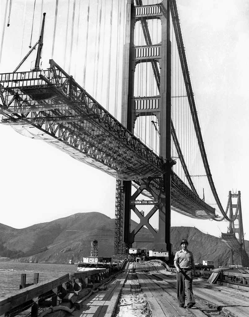 #33 A workman walks on the levee that connects Fort Point to the south tower of the Golden Gate Bridge while it is under construction, 1936.