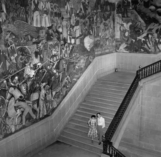 #19 A young couple walk down a staircase in a monumental building in Mexico City.