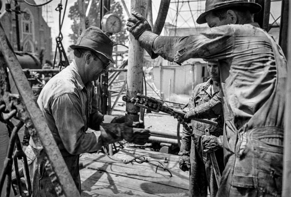 #4 A worker screws a nipple onto the end of a drill stem for a test to determine direction and draft of drilling operations.