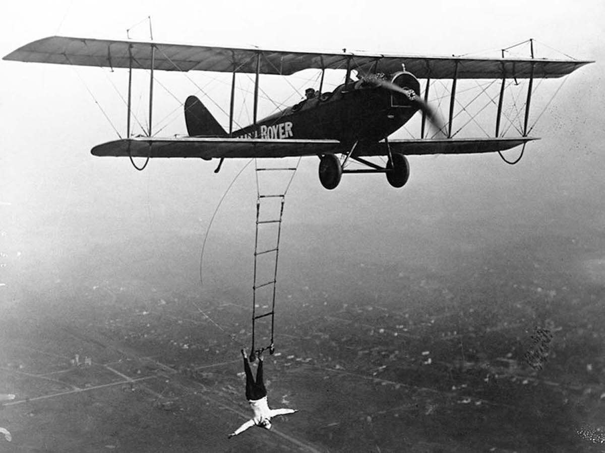 #7 Lillian Boyer hanging from right wing boom using her right hand, 1920s.